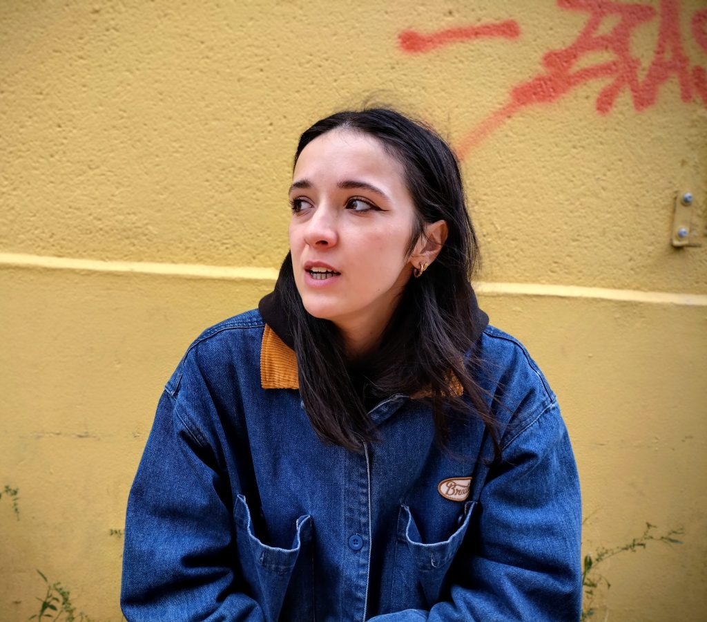 Camille parle devant un mur jaune