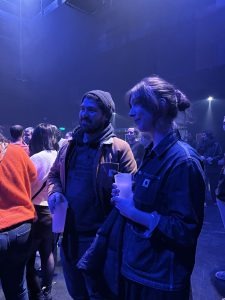Laura et son petit ami à l'attente du concert Ojos, le duo parisien. Pour Laura, c'est sa deuxième édition du festival Les Femmes S'en Mêlent puisque le groupe Ojos fait parti de son label. "J'ai déjà vu une autre artiste de mon label programmé par le festival Les Femmes S'en Mêlent à Stereolux il y a 2 ou 3 ans", souligne t-elle. Malgré le fait qu'elle connaisse déjà le festival, Laura explique : "je viens pour découvrir les artistes féminines car toujours des bonnes découvertes à Stereolux". Elle nous explique aussi son engagement vis-à-vis de la visibilité des femmes dans la musique : "c’est hyper important pour moi l’égalité des femmes et des hommes et je trouve que c’est vraiment un évènement qui met ça en lumière" en soulignant que "c’est une chose qui me tient à cœur au label". Laura confirme sa présence ce mardi : " c'est hyper important au point de vue professionnel mais aussi personnel d'aller voir des concerts comme ça qui défendent des causes minorisées" Date : 18/11/2025 Crédit photo : Lou Defois