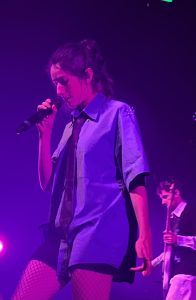 La chanteuse du duo parisien Ojos sur le devant de la scène. En arrière plan, son guitariste. Ojos, c'est un groupe de pop sombre et intense abordant des sujets engagés tels que la place de la femme dans la société actuelle. Date : 18/11/2025Crédit photo : Lou Defois