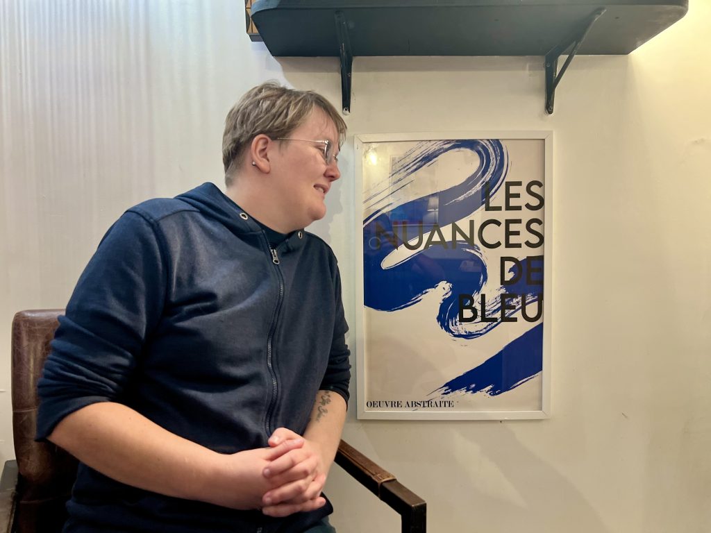 Lou Gates posant à côté d'un tableau dans le bar du Kraken à Nantes.